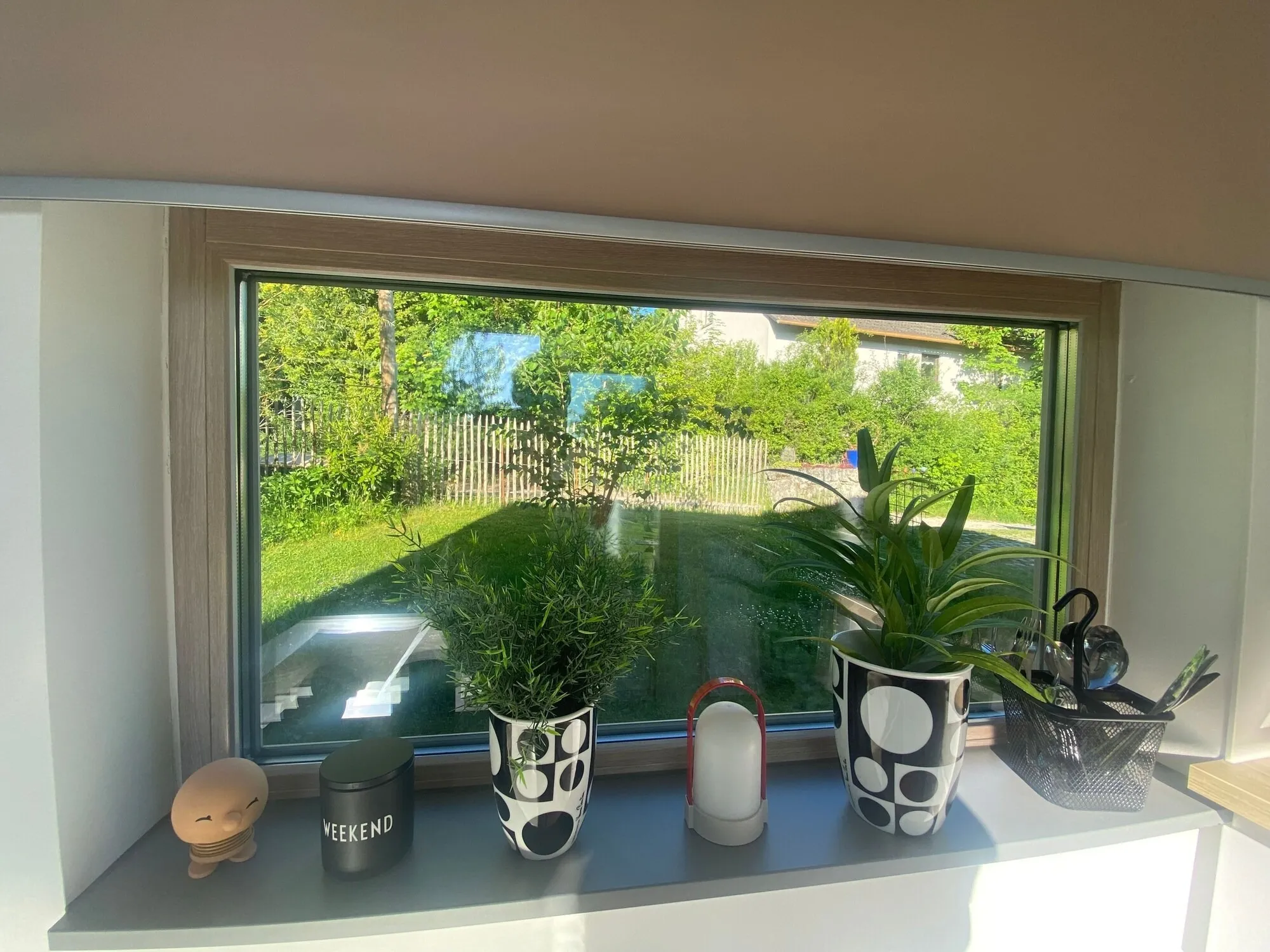 Fensterbank mit Pflanzen, Kerzen und Dekoration, dahinter der Garten