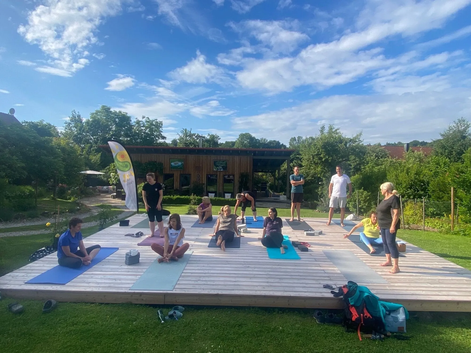 Yogagruppe auf dem Holzdeck auf dem Nachbargrundstück